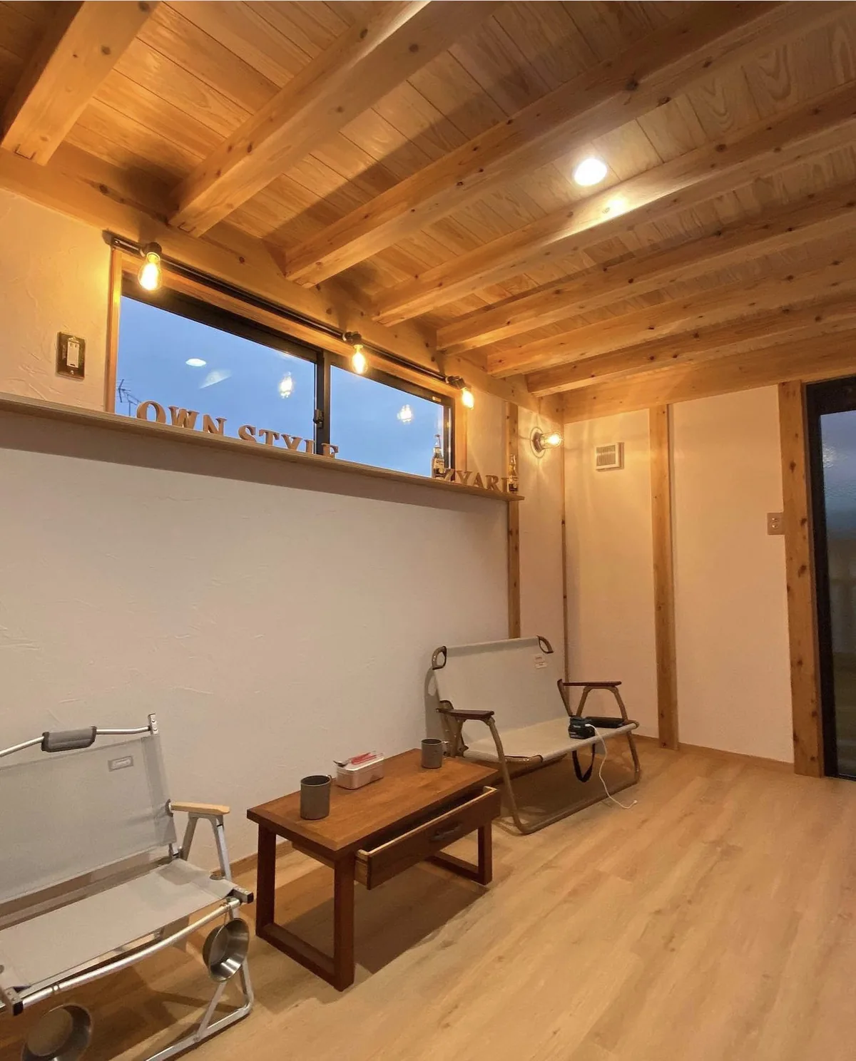 夕暮れの窓と暖かな照明に照らされた木の内装。事務所や店舗として使える小さな空間